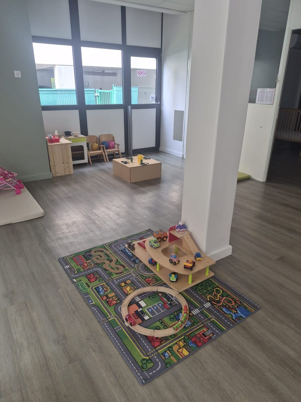 Un tapis de circuit avec un garage et des petites voitures en bois